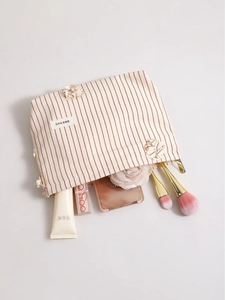 Beauty case in tela a righe rosse con trifoglio 3D e cosmetici su sfondo bianco pulito