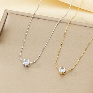 Détail de colliers en acier inoxydable argent et or avec pendentifs en zircone à six griffes