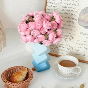 Dreistufige blaue geometrische Vase mit Farbverlauf und rosa Rosen auf weißem Tisch