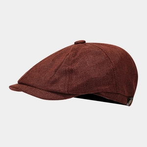 Detailed macro view of the textured linen-style fabric and metal button on a brown newsboy cap