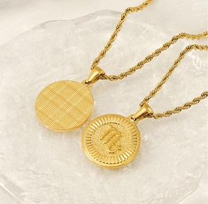 Detail of 18K gold zodiac necklaces featuring a textured round pendant and Scorpio sign