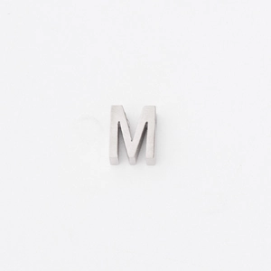 Close-up of polished silver titanium letter M charm with a small hole for jewelry making