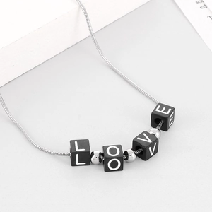 Detail of silver snake chain with LOVE letter blocks pendant on white surface