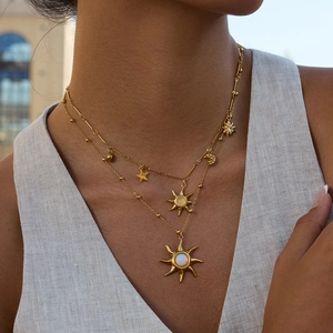Dettaglio di una collana dorata a strati con ciondolo a sole in opale e stelline