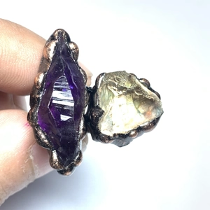 Detailed close-up of handmade irregular purple and yellow crystal stones on metal rings