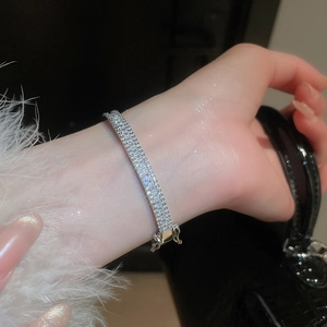Close-up of a silver zircon rectangle buckle bracelet worn on a wrist with shimmering finish