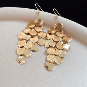 Detailed close-up of multilayered gold disc dangle earrings on an off-white display tray
