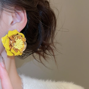 Gros plan de boucles d'oreilles fleurs 3D jaunes surdimensionnées portées par un mannequin