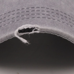 Macro shot of distressed grey cotton baseball cap brim with stylish ripped edge detailing