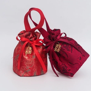 Detail of red brocade wedding candy bags with gold drawstring and metal Xi pendant