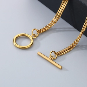 Detail of a gold stainless steel chain bracelet showing the brushed metal OT clasp closure