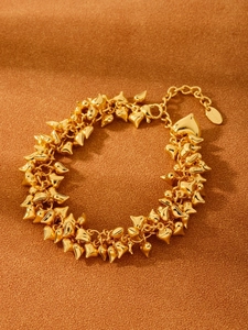Detailed view of S925 gold-plated heart charms on a tassel bracelet over a matte background