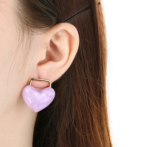 Elegant pink marble resin heart earrings with gold U-shaped metal hooks on model
