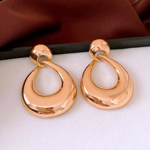 Detail showing high-polished gold teardrop geometric earrings with a vintage metallic finish