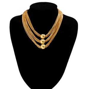 Close-up of layered gold box chain necklace with three round ball pendants on a black bust
