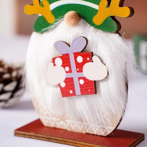 Close-up of wooden Christmas gnome with green striped hat and red gift box detail