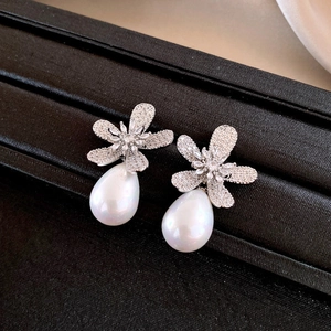 Detail of silver flower earrings with sparkling crystals and drop pearl pendants