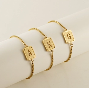 Detailed macro view of gold-plated titanium steel bracelets with hollow letter charms