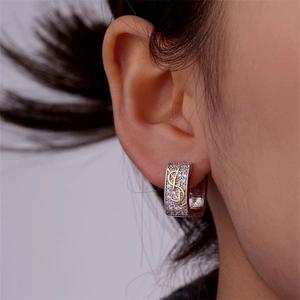 Close-up of sparkling rhinestone hoop earrings with a gold logo on a model's ear