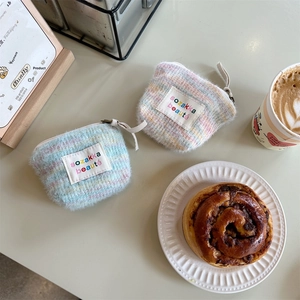 Close-up of mini plush rainbow makeup bags with zip closure and woven label on a table