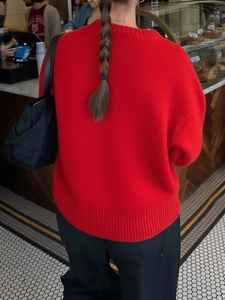 Rear view of a casual red long sleeve crew neck knitted sweater on a model in a cafe setting