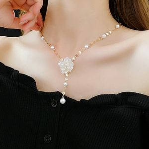 Detailed view of French-style gold necklace with floral pendant and pearls on a model