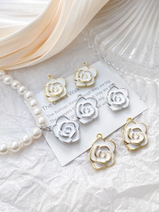 Close-up of 14k gold camellia flower pendants with white enamel on silk and pearls