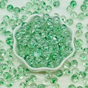 Macro view of 8/10mm light green floral glass beads for DIY jewelry making in a white bowl