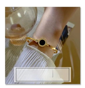 Detailed view of Roman numeral gold bangle with black shell inlay and sparkling stone