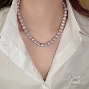 Detail of lavender pearl necklace worn on a white shirt showing smooth lustrous beads