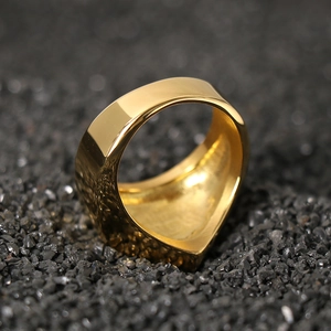Macro view of a gold geometric pyramid ring set on a black stone background