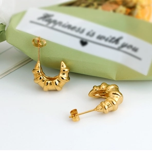 Detailed macro view of golden croissant hoop earrings with a spiral twisted texture