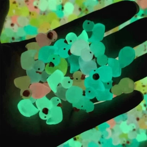 Glow in the dark mini resin ducks held in hand showing vibrant fluorescent light effect