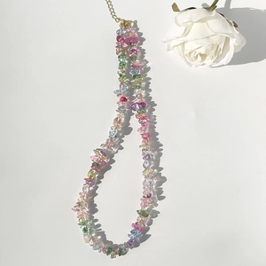 Detail of colorful crystal gravel necklace with gold chain and white rose on white background