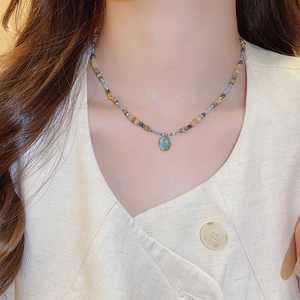 Detail of beaded necklace with oval turquoise pendant on model for bohemian style