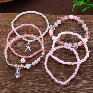 Dettaglio di braccialetti bohémien a più strati rosa e bianchi con ciondolo a stella