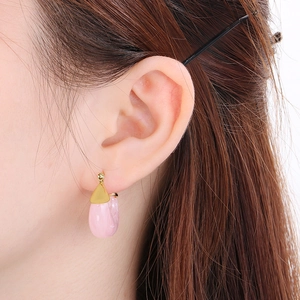 Close-up of model wearing pink jelly resin drop earrings with golden metal details
