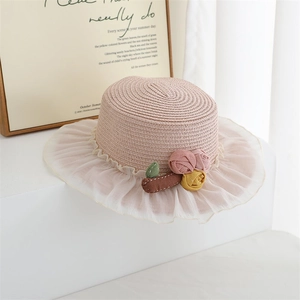 Detailed close-up of a pink straw hat with lace ruffle and floral embellishment for girls