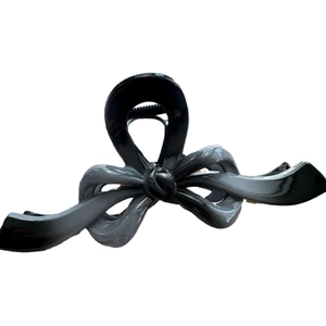 Large black bow-shaped hair claw clip with irregular lines and glossy resin finish