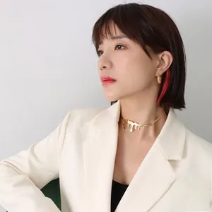 Close-up of gold drip choker and hoop earrings on model for a modern fashion look