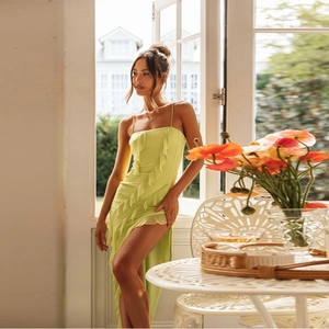 Détail de robe vert citron avec fines bretelles, volant au décolleté et fente latérale