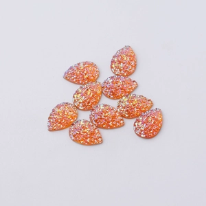 Macro shot of orange teardrop resin charms with shimmering glitter crystal texture