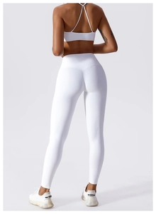 Detail of white cross-back yoga bra and high-waist leggings on a fitness model