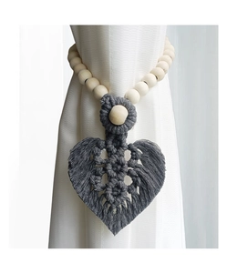 Detail of hand-woven cotton leaf curtain tieback with natural wood beads on white sheer curtain