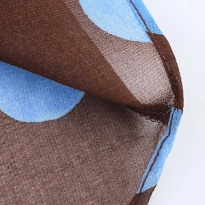Detail of sheer brown fabric with blue polka dots and professional hemmed edge craftsmanship