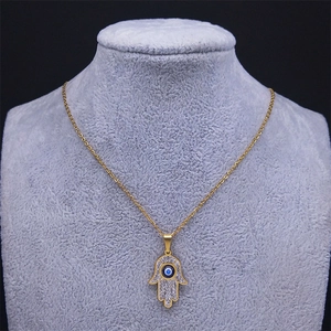Macro detail of Hamsa hand pendant with blue evil eye and pavé crystals on a gold chain