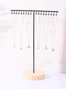 Minimalist black metal T-bar necklace stand with round wooden base and gold pendants