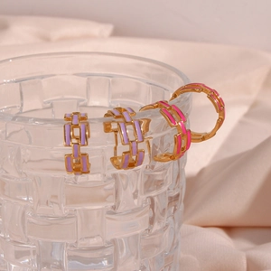 Detail of pink and purple enamel chain earrings on a glass rim with silk background
