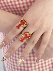 Vue détaillée de deux adorables bagues homard rouge en émail sur une main décorée.