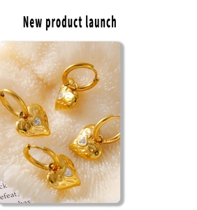 Macro detail of 18k gold heart earrings with hammered texture and zircon inlays